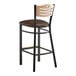A Lancaster Table & Seating black bistro bar stool with a natural wood seat and brown cushion.