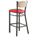 A Lancaster Table & Seating black bistro bar stool with natural wood back and red vinyl seat.
