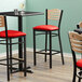 A Lancaster Table & Seating black bistro bar stool with a detached red vinyl seat.