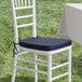 A white chair with a navy blue cushion tied on top.