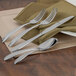 A set of 12 Walco Bellwether stainless steel salad forks on a table with a white tablecloth and napkin.