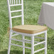A white chair with a Lancaster Table & Seating tan cushion on the seat.
