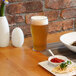 A table set with a bowl of noodles and a glass of beer served in a white Front of the House Tritan plastic pint glass.