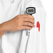 A person wearing a white Uncommon Chef long sleeve chef coat with a digital thermometer in the pocket.