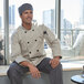 A man in a Uncommon Chef long sleeve chef coat sitting on a window sill.
