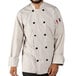 A man wearing a white Uncommon Chef long sleeve chef coat with 10 buttons smiles.