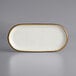 An oval white stoneware platter with brown specks and a brown rim.
