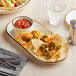 An Acopa vanilla bean stoneware oblong coupe platter with nachos and salsa on a table.