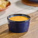 A small blue porcelain ramekin filled with a creamy orange dip.