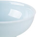 A close-up of a white Thunder Group Blue Jade melamine bowl with a blue rim.