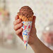 A hand holding a Keebler Colosso jacketed waffle cone with chocolate ice cream.