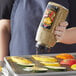 A woman pours McCormick Grill Mates Vegetable Seasoning onto grilled vegetables.