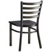 A black metal Lancaster Table & Seating ladder back chair with a black wood seat.