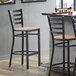 A Lancaster Table & Seating ladder back bar stool with a natural wood seat.