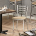 A Lancaster Table & Seating ladder back chair with a natural wood seat next to a table in a restaurant.