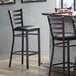 A Lancaster Table & Seating distressed copper ladder back bar stool with a black vinyl padded seat.
