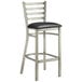 A Lancaster Table & Seating silver metal ladder back bar stool with a black vinyl padded seat.