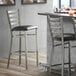 A Lancaster Table & Seating ladder back bar stool with a black vinyl cushion.