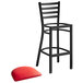 A black metal Lancaster Table & Seating ladder back bar stool with a red padded seat.