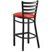 A Lancaster Table & Seating black ladder back bar stool with red vinyl padded seat.