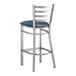 A Lancaster Table & Seating metal bar stool with a navy blue cushion on the seat and ladder back.