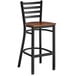 A Lancaster Table & Seating black ladder back bar stool with a wooden seat.