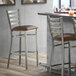 A Lancaster Table & Seating ladder back bar stool with a dark brown vinyl padded seat.