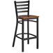 A Lancaster Table & Seating black finish ladder back bar stool with an antique walnut wood seat.