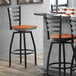A Lancaster Table & Seating black metal bar stool with a cherry wood seat.