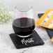 A glass of red wine on an Acopa black slate coaster next to cheese with a personalized message.