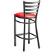 A Lancaster Table & Seating distressed copper metal ladder back bar stool with a red padded seat.