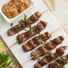 A plate of Les Chateaux de France unmarinated beef satay skewers with a bowl of peanut sauce.