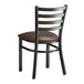 A black metal Lancaster Table & Seating ladder back chair with a dark brown vinyl cushion.