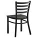 A black Lancaster Table & Seating metal ladder back chair with a wooden seat.