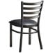 A Lancaster Table & Seating black metal ladder back chair with black vinyl cushion.