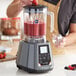 A person using an AvaMix blender to make a smoothie with berries.