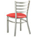 A Lancaster Table & Seating metal restaurant chair with red padded seat and ladder back.