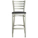 A Lancaster Table & Seating metal bar stool with black wood seat and ladder back.