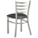 A Lancaster Table & Seating metal ladder back chair with a black vinyl padded seat.