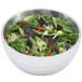 A Vollrath double wall metal serving bowl with salad containing green leaves and red peppers.