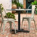 A Lancaster Table & Seating Excalibur black outdoor table base with chairs on a brick patio.
