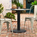 A Lancaster Table & Seating Excalibur outdoor table base with chairs on a brick patio.