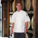A man wearing a white Uncommon Chef short sleeve chef coat with customizable embroidery.