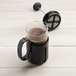 An OXO Tritan French coffee press with a cup of coffee on a white background.