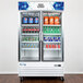 An Avantco swing glass door refrigerator filled with drinks on shelves.
