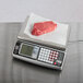 A piece of raw meat on a San Jamar digital price computing scale with a paper towel.