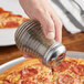A hand using an American Metalcraft beehive spice shaker with a chrome-plated top to put pepper on a pizza.