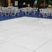 A Palmer Snyder white portable dance floor with silver trim set up over a large area with tables and chairs.