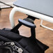 A black backpack hanging from a Luxor stackable desk chair