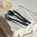 A black plastic spoon and fork on a napkin.